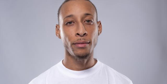 Litebulb is a young, lightskinned Black man with short hair. He wears a white t-shirt.